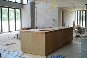 El enfoque selectivo en la isla de cocina de madera en instalación en la casa en construcción foto