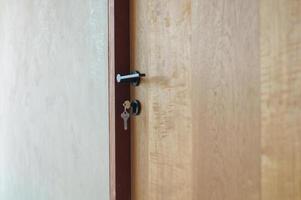 Selective focus on modern style of knob on wooden door with keys hanging on lock photo