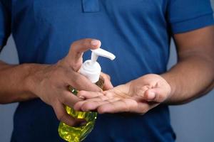 La mano del joven con gel desinfectante para prevenir el virus foto