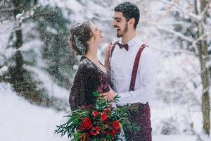 Groom in a brown and bride in burgundy in the mountains