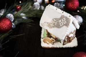 Casa de pan de jengibre en el esmalte blanco en el fondo de las decoraciones navideñas foto