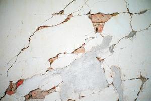 Abstract texture and background of broken plastered cement wall with red bricklayers inside photo