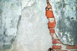 Abstract texture and background of broken plastered cement wall with red bricklayers inside photo