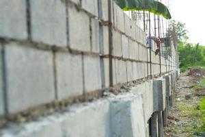 Paisaje del sitio de construcción con muro de albañil de hormigón y la mano del trabajador instalando los ladrillos en la pared foto