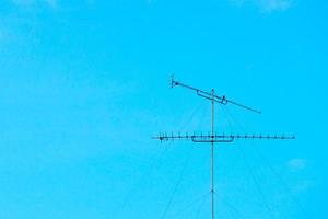 Rusted old steel antenna tower isolated on clear blue sky background with motion blurred bird holding on the bar photo