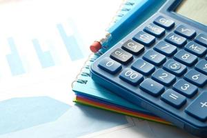 Close up of blue calculator and financial chart on table photo