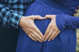 Pregnant couple with hands in a heart shape photo