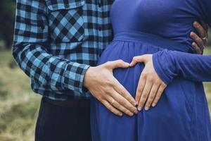 Pregnant couple holding belly with heart photo