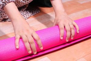 Woman rolling pink exercise mat photo