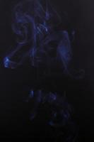 El humo del cigarrillo blanco sobre un fondo negro oscuro foto