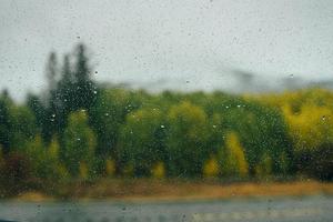 Raindrops on window with autumn background photo