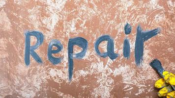 Written on the wall the word repair and a brush in hand photo