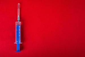 Medical syringe on a red background with copy space photo