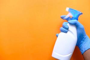 Person hand in disposable gloves holding disinfectant spray photo