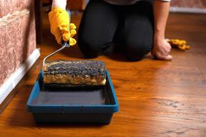 Girl holds a paint roller and a container with gray paint photo