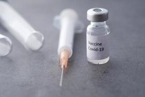 Cerca de la vacuna contra el coronavirus y la jeringa sobre fondo negro