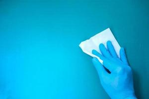 Mano en guantes de goma azul mesa de limpieza con paño foto