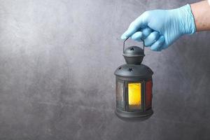 Hand holding lantern on grey background photo