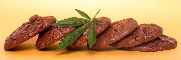 Marijuana oatmeal cookies and green leaf of cannabis on a yellow background