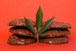 Sweets with marijuana on red background photo