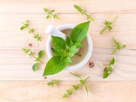 Hojas de albahaca de limón y flores sobre fondo de madera foto