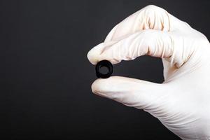 Hand in a white sterile glove holds piercing tunnel in black color photo