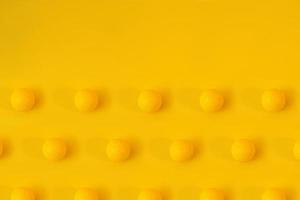 Yellow golf balls on yellow background creative concept. Monochrome color scheme. Repetitive texture pattern. photo