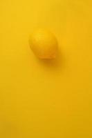 Yellow lemon isolated on clean yellow background. Abstract minimal concept. photo