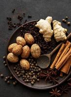 Gingerbread spices on slate - star anise, cinnamon, cloves, nutmeg, ginger, cardamom, and black pepper photo