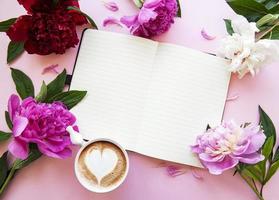 flores de peonía, cuaderno y café foto