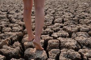 Mujer caminando sobre tierra seca agrietada foto