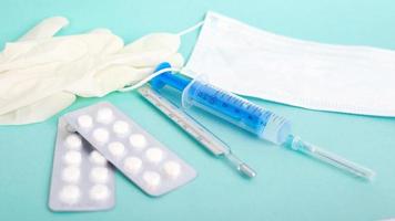 Mask, respirator, thermometer, pills and syringe on blue background photo