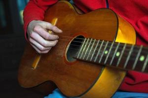 Musician in red plays an acoustic guitar photo