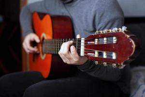 Girl playing a six string acoustic guitar with nylon strings photo