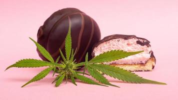 Chocolate marshmallows and cannabis bud on a pink background photo