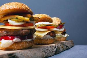 Three burgers on a wooden forest stand on a gray background photo