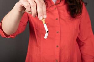 Broken cigarette in female hands, stop smoking sign photo