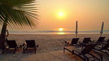 guarda-sóis vazios e cadeiras de praia ao pôr do sol