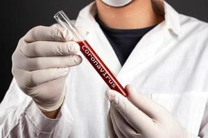 El médico sostiene un tubo de ensayo con sangre infecciosa de la enfermedad viral respiratoria covid-19 foto