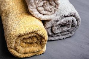 Tres toallas enrolladas y dobladas de color pastel sobre un fondo gris foto