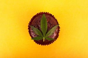 Hoja de cannabis y pastel dulce sobre fondo amarillo foto