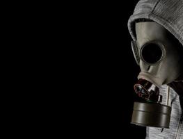 Hombre con una máscara de gas sobre un fondo negro, protección contra virus foto