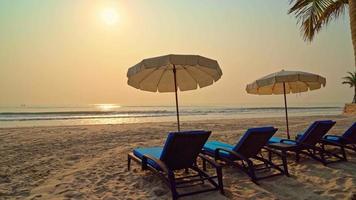 offene Sonnenschirme und Liegestühle am Strand