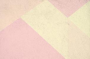 Formas geométricas de color rosa y amarillo pintadas en una pared de hormigón con textura al aire libre como telón de fondo con textura foto