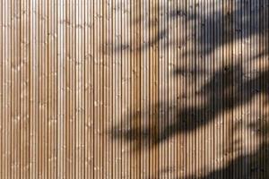 Fondo de fachada de madera moderna con textura de fondo de paneles de madera de sombra de árbol