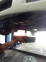 Mechanic draining engine oil from a car photo