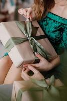 Girl holding a present in hands, women with gift box in hands wrapped in decorative craft paper with a tied green ribbon bow, top view, concept holiday, love and care photo