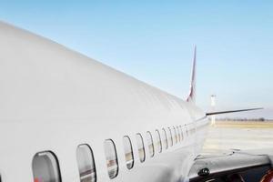 Aircraft porthole side window airplane. White heavy passenger jet engine airplane on the runway at the airport against blue sky, aviation transportation theme background photo