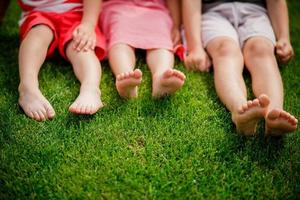 Bare legs of little girls sitting on the grass.