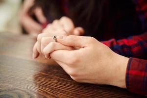 hombre sosteniendo la mano de su novia. Hombre haciendo una propuesta de matrimonio a su novia - pareja felizmente comprometida cogidos de la mano. amor, familia, concepto de aniversario. foto